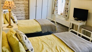 A room with two beds, a television, and a window with curtains. - Charming 2 Bed House Near Rhoscolyn,discounts FOR (Holyhead)