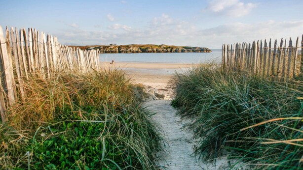 A sandy beach path leading to a calm sea with a small island in the distance. - Charming 2 Bed House Near Rhoscolyn,discounts FOR (Holyhead)