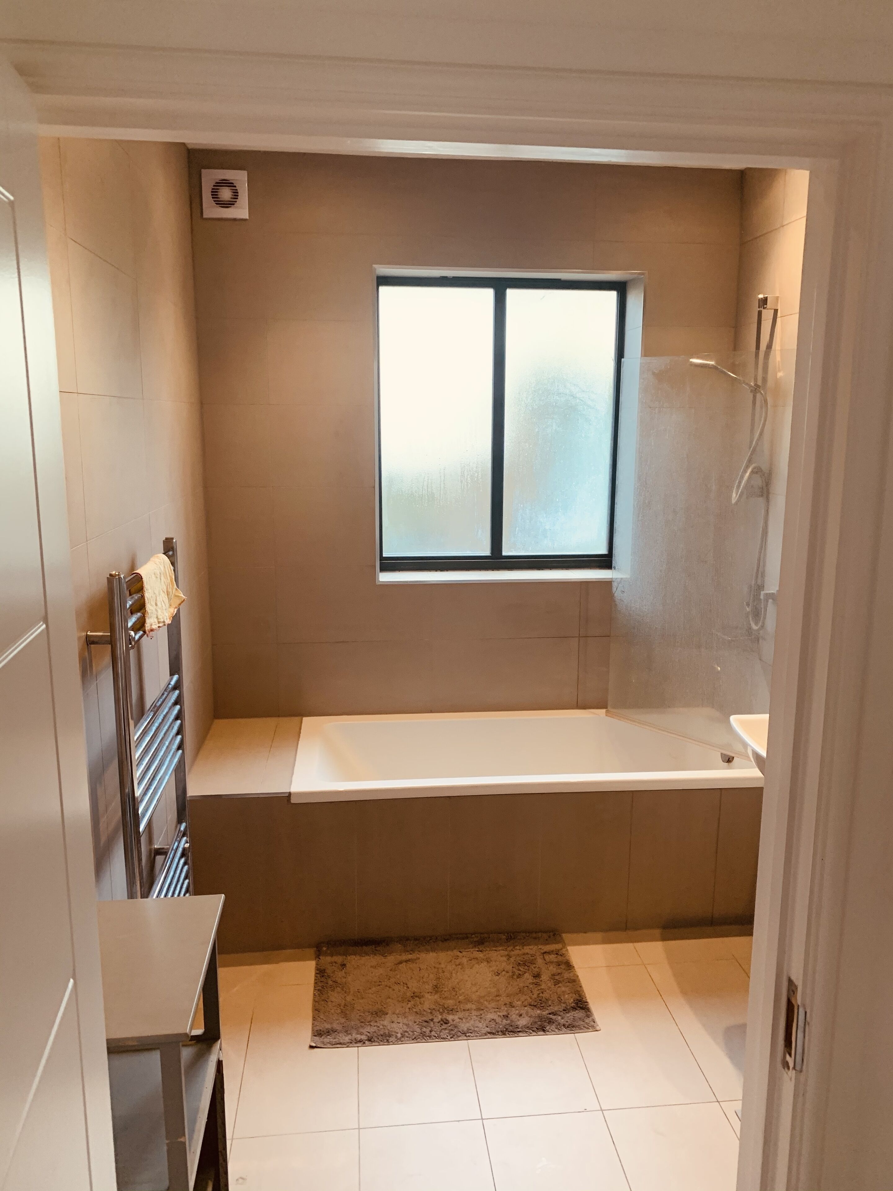 A modern bathroom with a bathtub, a window, and a shower.