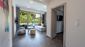 A modern living room with a sofa, ottoman, and a glass table. - SunBlue Villa Modern Private Pool (thasos)