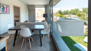 A modern dining area with a table and chairs, a sofa, and a large window with a view of the neighborhood. - SunBlue Villa Modern Private Pool (thasos)