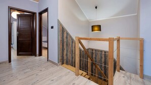 A staircase with wooden railings and a metal handrail, leading to an upper floor.