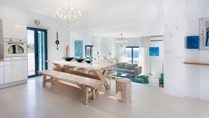 A spacious kitchen with a wooden table, benches, and a chandelier. - Villa Chryssi - Hilltop Escape w/ Endless Sea Views by etouri (Chania)