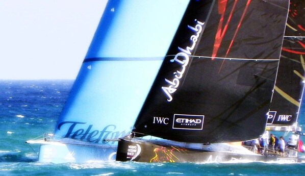 A sailboat with 'Abu Dhabi' and 'IWC' logos, sailing on the ocean. - Apmto Playa 12 Rocafel 5 (Alicante/Alacant)