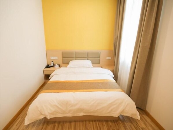 Una camera d'albergo con un letto, un comodino e una tavola da notte.