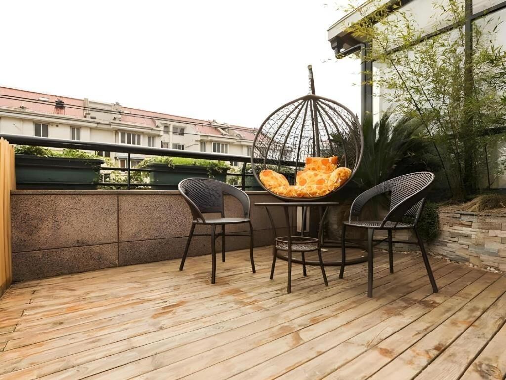 An outdoor patio with a round table and two chairs, a hanging chair, and a view of buildings in the background.