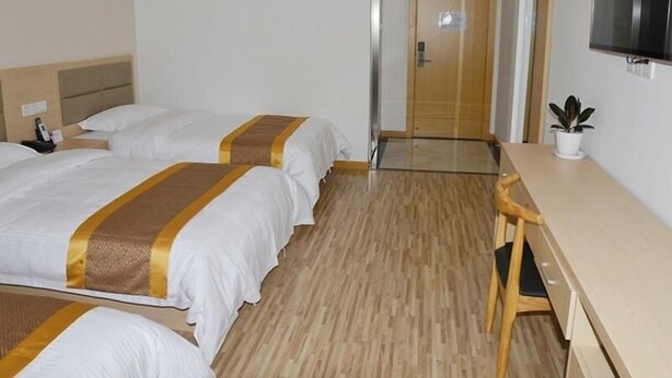 Een hotelkamer met twee bedden, een bureau, een stoel, een televisie en een deur.