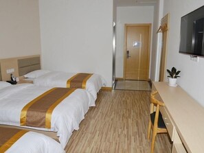 Una camera d'albergo con due letti, una scrivania, una sedia, una televisione e una porta.