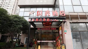 Een hotelentree met een rode loper, glazen deuren en een bord met Chinese tekens.