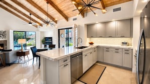 A modern kitchen with a large island, stainless steel appliances, and a herringbone tile backsplash. - Modern Life | Chic 1BR Getaway with Expanded Outdoor Living Spaces – a Greenday property (Rancho Mirage)