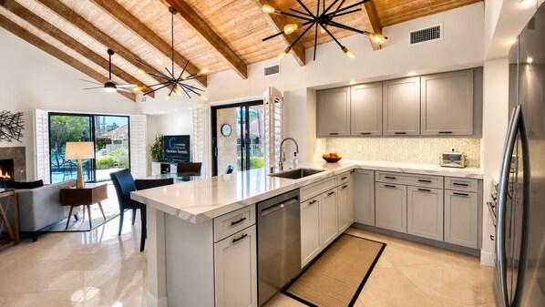 A modern kitchen with a large island, stainless steel appliances, and a herringbone tile backsplash.