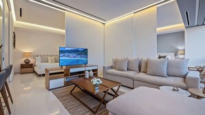 Ein modernes Wohnzimmer mit Flachbildfernseher, einer Couch, einem Couchtisch und einem Essbereich mit Stühlen.