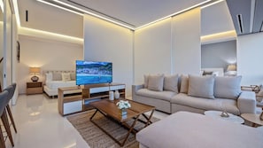 Un salon moderne doté d’un téléviseur à écran plat, d’un canapé, d’une table basse et d’un coin repas avec des chaises.