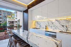 Une cuisine moderne dotée d’un plan de travail en marbre, de meubles de rangement intégrés et offrant une vue sur un quartier résidentiel.