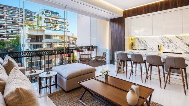 Eine moderne Wohnung mit Balkon, Essbereich und einer Küche mit Marmorarbeitsplatten.