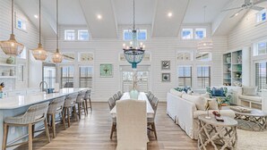 A spacious kitchen with a central island, a dining area with a chandelier, and a living room with a sofa and coffee table. - Designer Lakefront Home@Cinnamon Shore South w/ Resort-Like Amenities (Port Aransas)