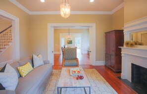 Una sala de estar con un sofá, una mesa de centro con fruta, una chimenea y una escalera.