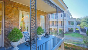 A brick building with a porch, two rocking chairs, and potted plants. - Gorgeous Estate Near Forsyth w/ Parking, Courtyard by Lucky Savannah (Savannah)