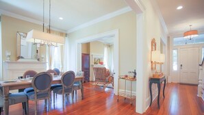 A spacious dining area with a wooden table and chairs, a chandelier, and a mirror above the table. - Gorgeous Estate Near Forsyth w/ Parking, Courtyard by Lucky Savannah (Savannah)