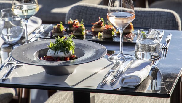 Un ambiente de restaurante con mesas dispuestas para comer, con platos, vasos y cubiertos.