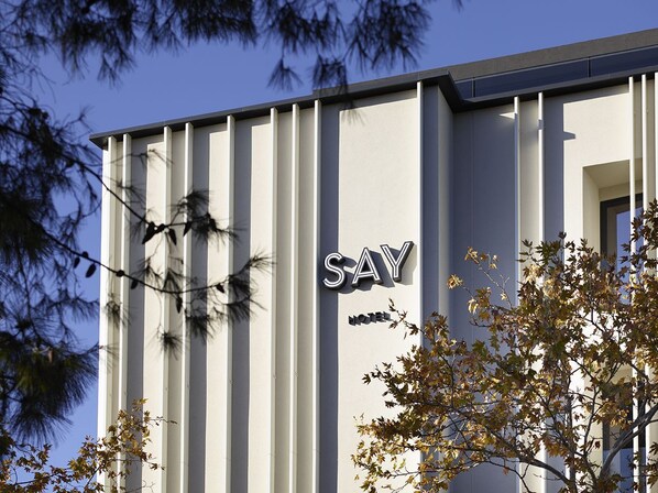 Une façade d’hôtel moderne, caractérisée par des lignes verticales, sur laquelle le nom « SAY HOTEL » est clairement affiché.