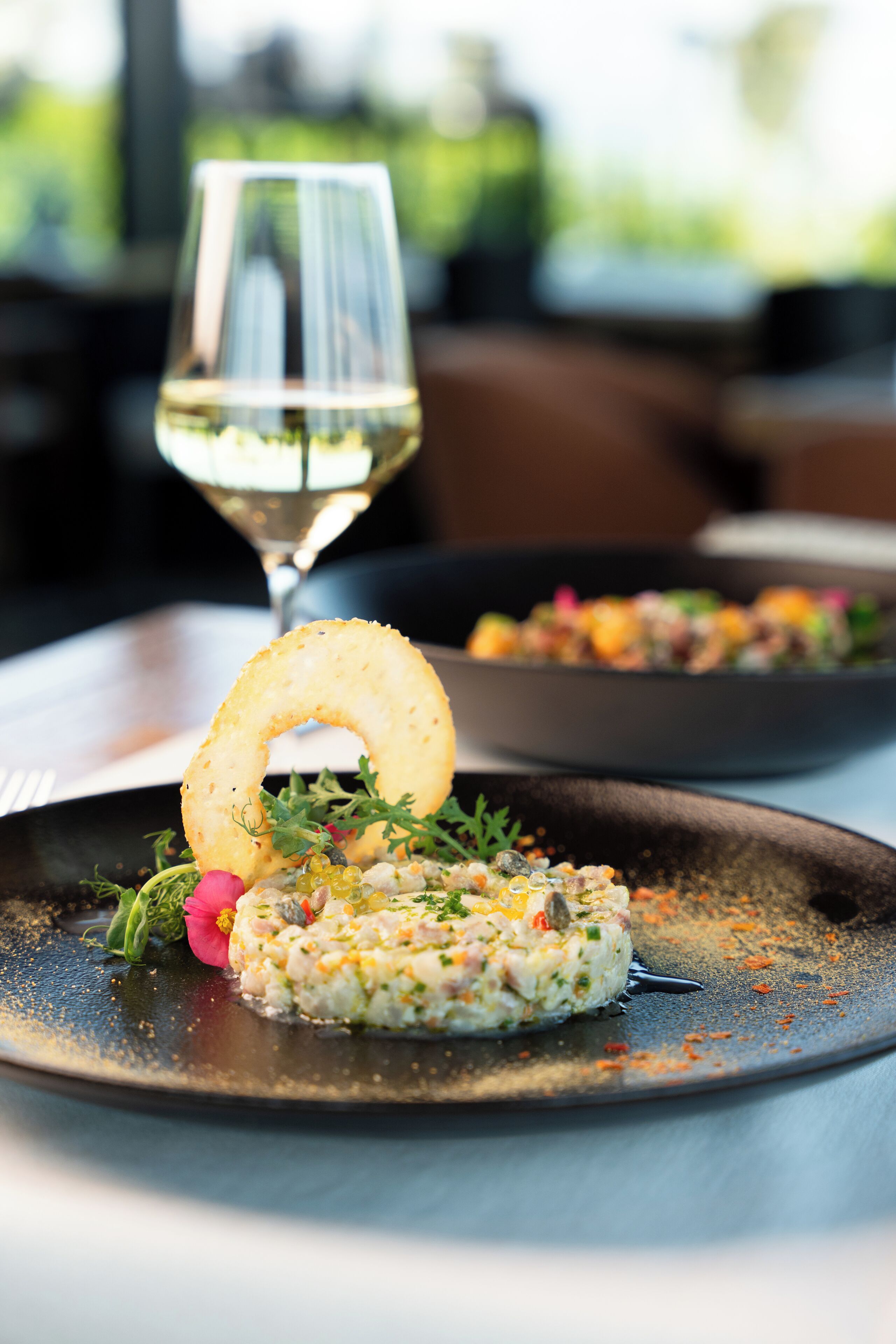 A plate of food with a glass of white wine on a table.