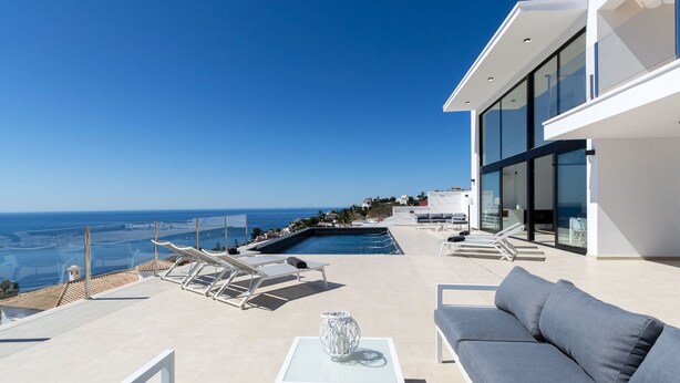 Une terrasse extérieure moderne dotée d’une piscine, de chaises longues et d’un canapé.