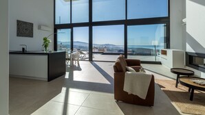 Un espace de vie moderne comprenant une cuisine, un coin repas et un espace détente près d’une grande fenêtre donnant sur un paysage magnifique.