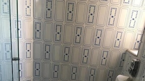 A bathroom with a patterned wall, a toilet, and a glass shower enclosure. - Binder Hotel Mogi Guaçu (Mogi-Guaçu)