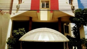 A tall building with a red and white facade, multiple balconies, and a covered entrance area. - Binder Hotel Mogi Guaçu (Mogi-Guaçu)