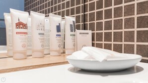 Et badeværelsesbord med forskellige toiletartikler, herunder brusebad, shampoo, hårkur og en badehue.