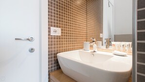 Et moderne badeværelse med en stor vask, et spejl og et bruseområde.