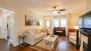 A living room with a striped sofa, a coffee table, a piano, and a fireplace. - One of a kind single family home, 6 bedrooms, sleeps 13 (Ocean City)
