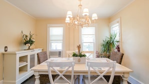 A dining room with a white table, two chairs, a chandelier, and a potted plant. - One of a kind single family home, 6 bedrooms, sleeps 13 (Ocean City)
