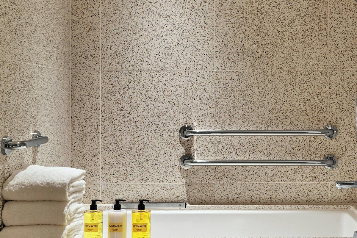 A bathroom with a bathtub, grab bars, and toiletries.