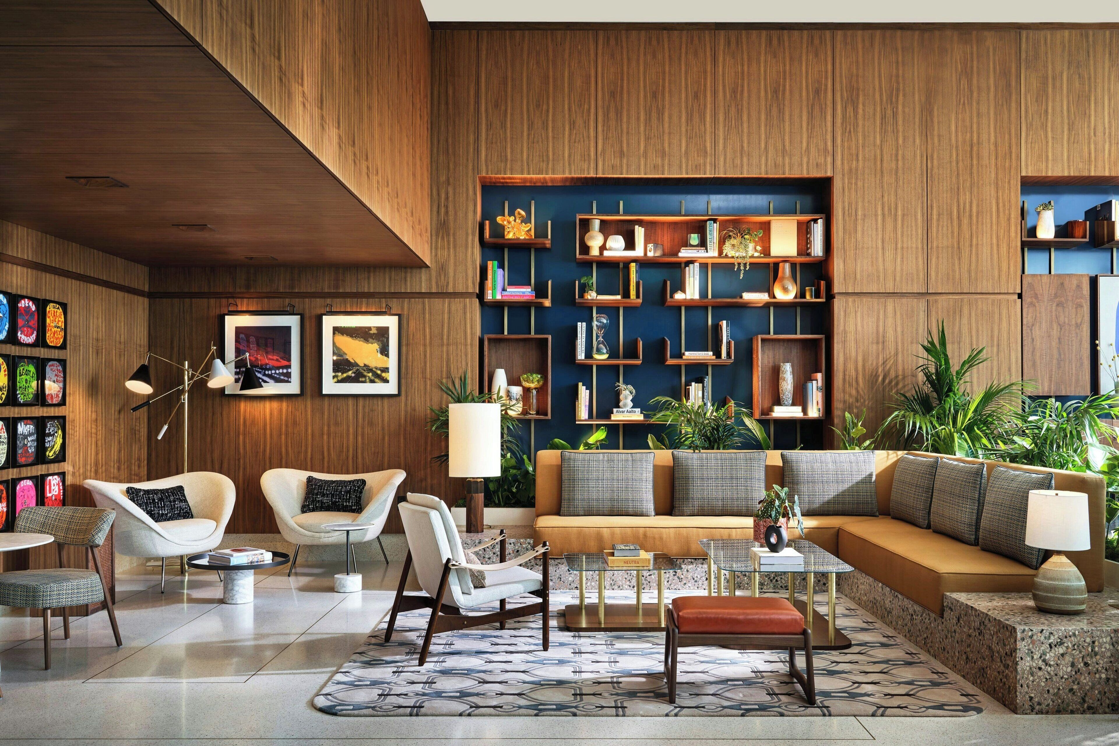 A modern living room with a wooden wall, a sofa, chairs, a coffee table, and a bookshelf.