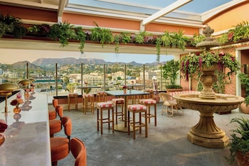 A bar area with wooden furniture and a well-lit bar counter. at The Hollywood Grande, Autograph Collection