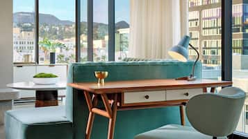 A modern living room with a teal sofa, a wooden desk, and a green chair.