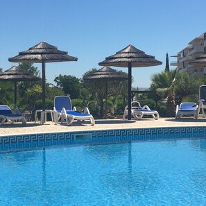 A poolside area with lounge chairs and umbrellas.