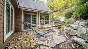 A house with a stone patio, a hammock, and a stone wall. - Cozy Family Mountain Home in Seven Springs (CHAMPION)