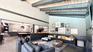 Un espacio moderno con mesa de billar, asientos cómodos y zona de cocina.