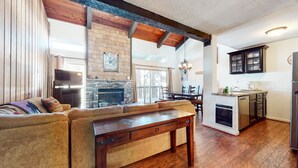 Una sala de estar acogedora con chimenea, vigas de madera y un comedor con vistas al exterior.
