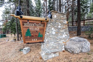 Discover Hidden Valley Village 153, nestled among pine trees and surrounded by a natural stone wall.
