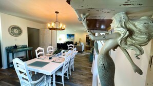 A dining area with a white table, chairs, and a chandelier. - Beautiful home with pool. See notes about heated pool season. (Tybee Island)