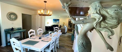A dining area with a white table, chairs, and a chandelier.