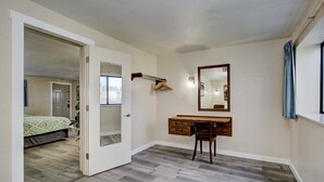 A bedroom with a wooden floor, a desk with a chair, a mirror, and a door leading to another room. - Weiser Motel & RV Park (Weiser)
