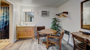A small room with a wooden vanity, a round table with chairs, a potted plant, and a mirror with lights. - Weiser Motel & RV Park (Weiser)