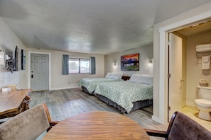 A bedroom with a bed, a window, a door, and a bathroom visible through an open door.