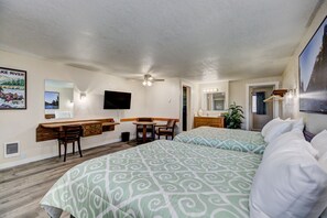 A hotel room with two beds, a desk with a chair, a television, and a bathroom with a mirror and lights. - Weiser Motel & RV Park (Weiser)