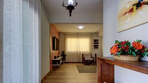 A hallway with a wooden floor, a dining area with a table and chairs, a potted plant, and a wall-mounted light fixture. - Casa 25pessoas c piscina Porto das Dunas (Aquiraz)